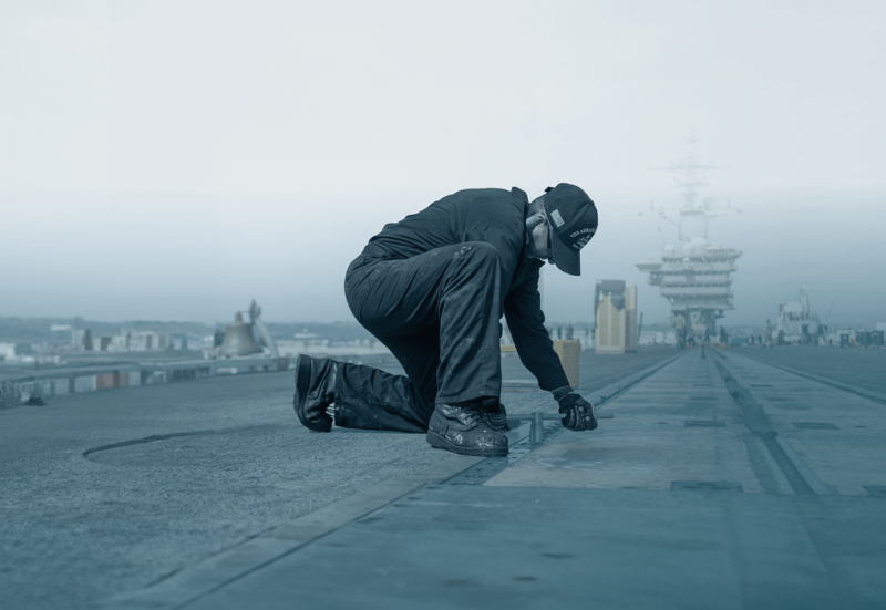 man repairing navy ship