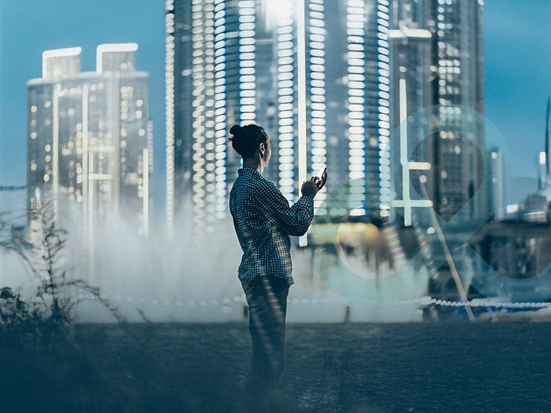 person using phone in front of cityscape