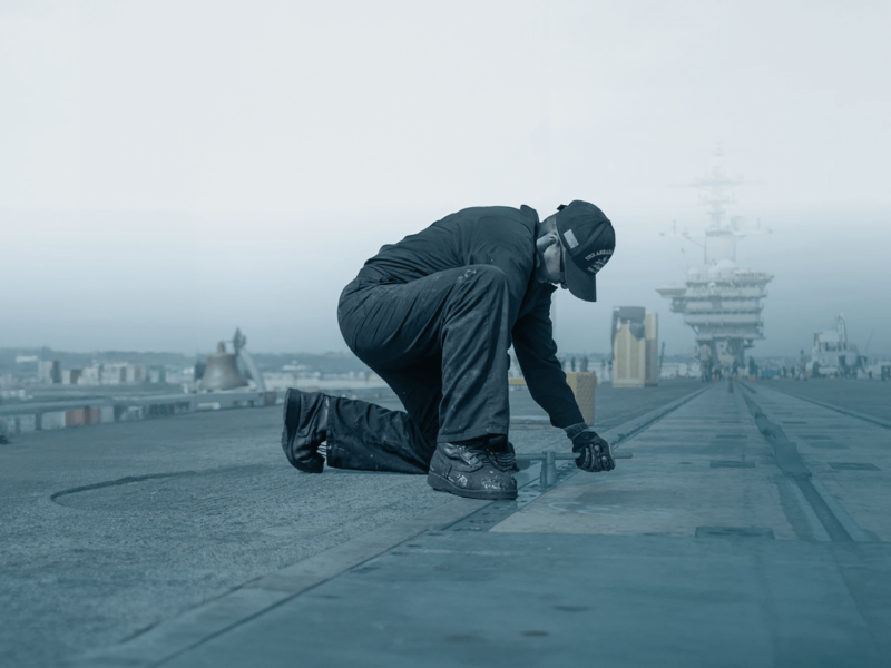 man repairing navy ship
