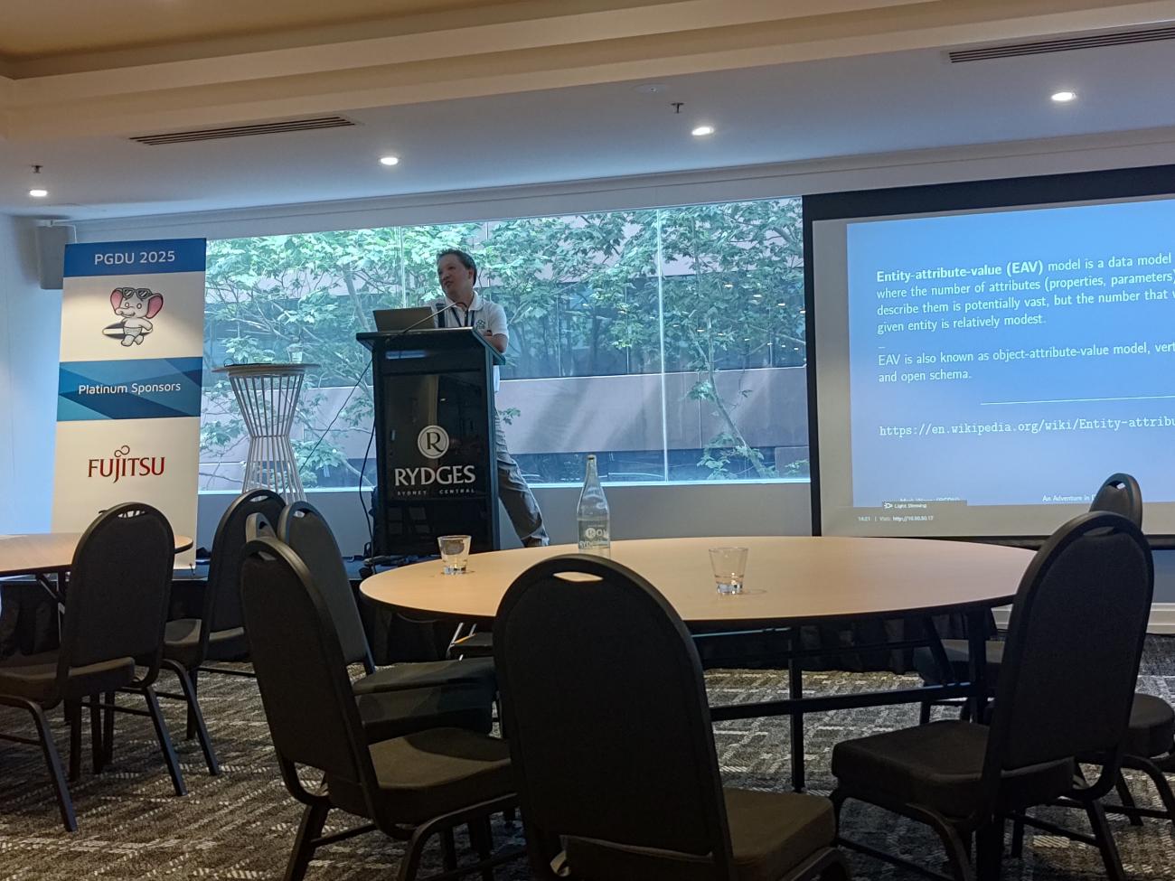 Mark Wong at Postgres Down Under, presenting in front of a screen