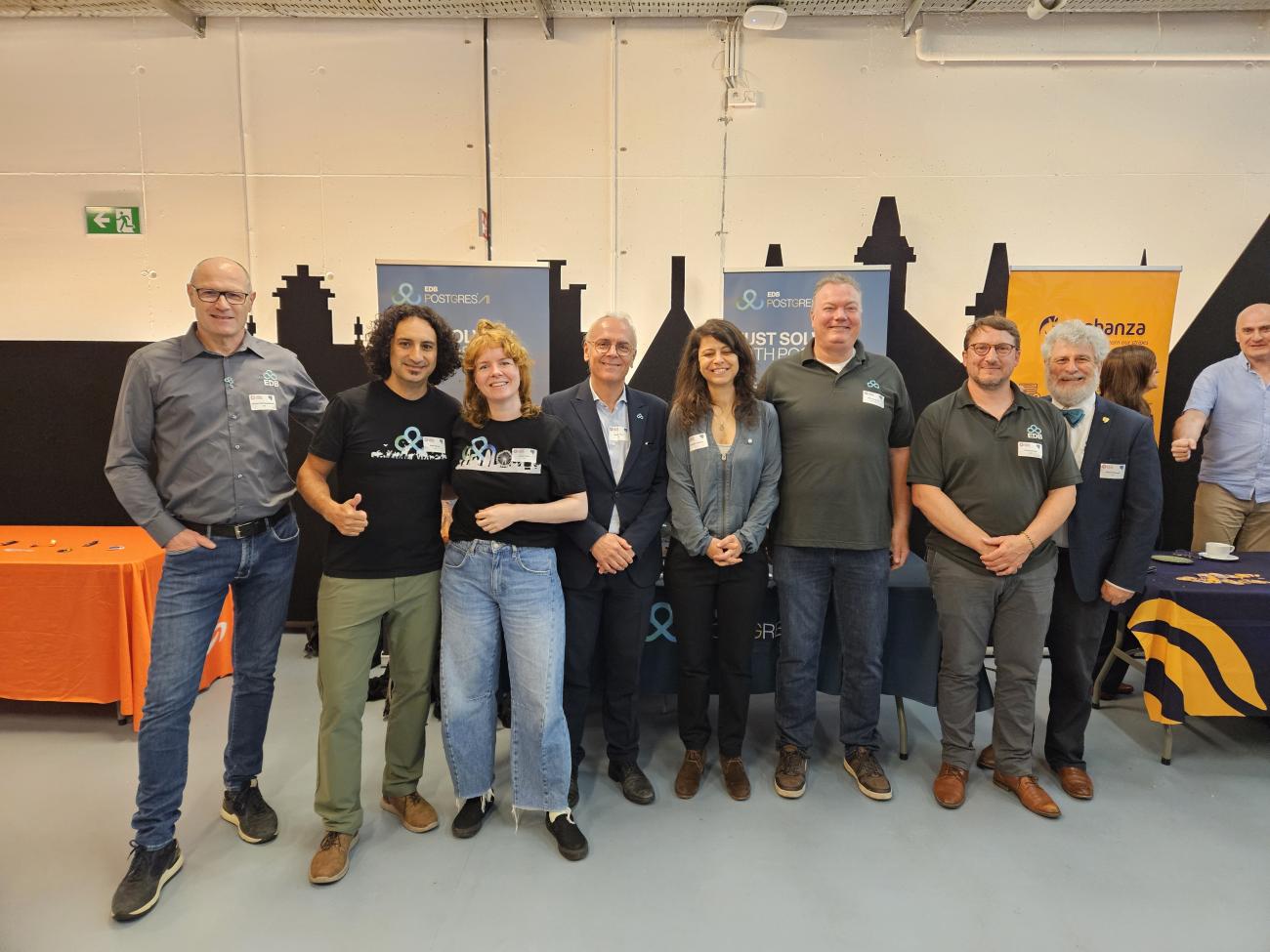 Group photo at PGConf BE  in front of 2 EDB banners: Hedwig, Boriss, Floor, Gianni, Afroditi, Niels, Xavier, and Bruce