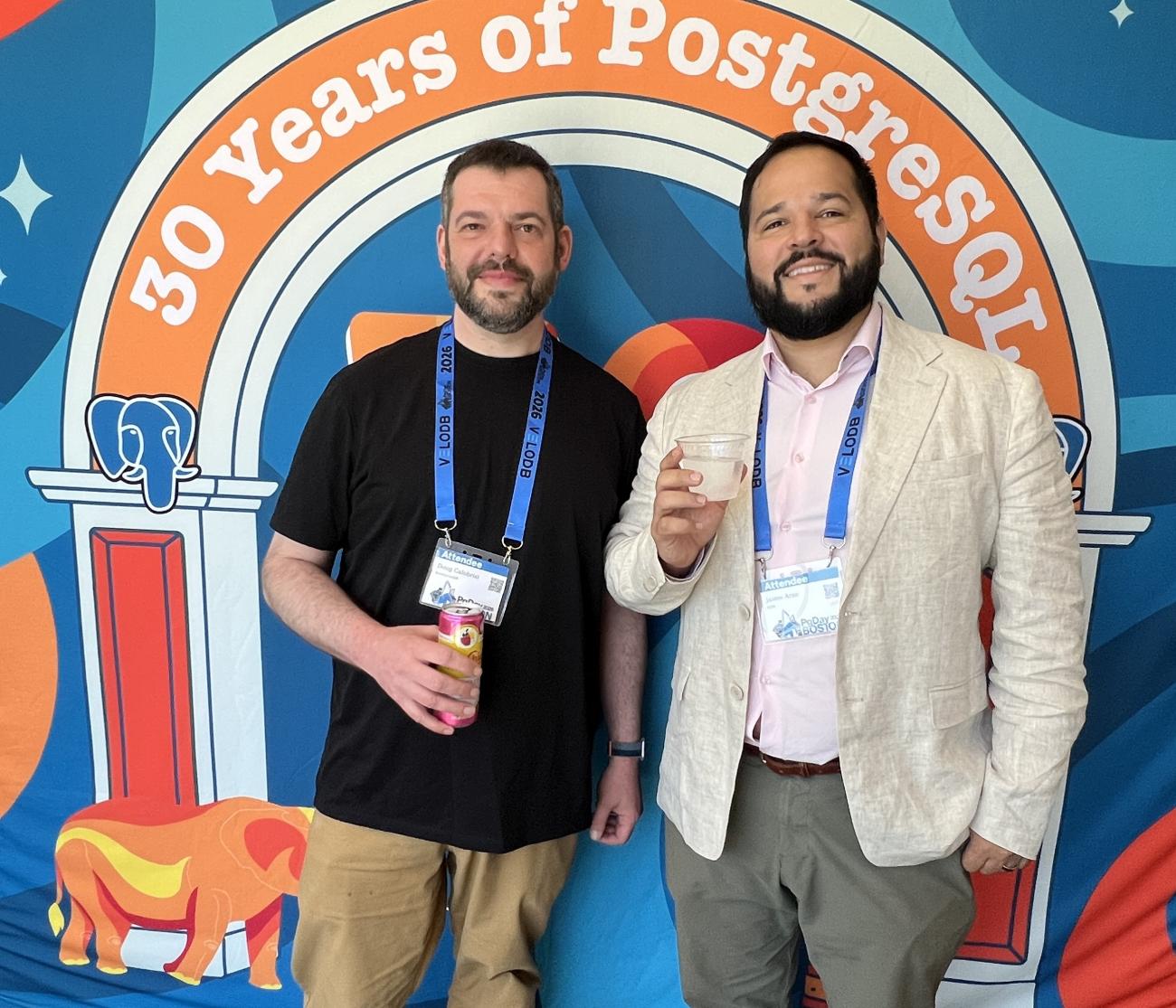 Doug Calobrisi and Jaime Arze in front of a banner saying "30 years of PostgreSQL"
