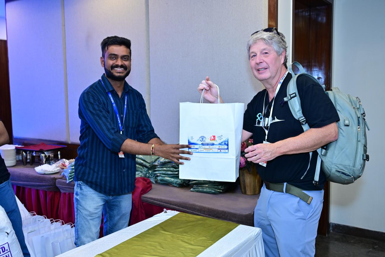 Tom Kincaid gets his goodie bag at the PgPune registration desk